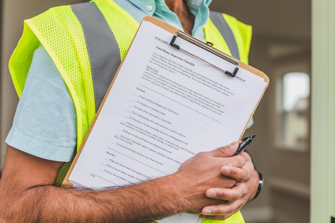 Professional roofing inspector with safety vest conducting a thorough building inspection checklist